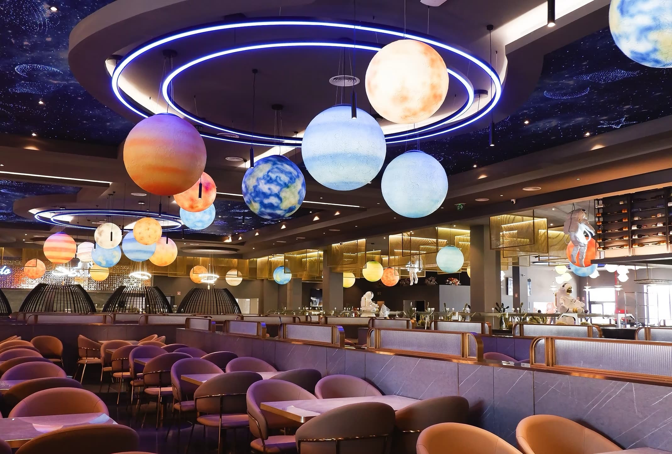 Interior amplo do Star Wok com planetas iluminados, teto estrelado e detalhes em cobre